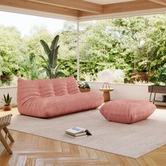 a living room filled with lots of furniture and plants on top of a hard wood floor