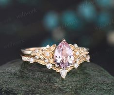 a pink diamond ring sitting on top of a rock