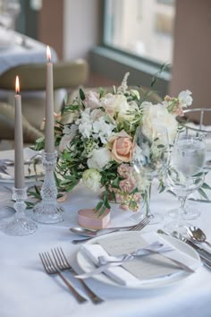 the table is set with silverware and flowers in vases, candles, and napkins