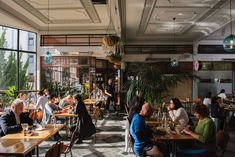 people sitting at tables in a restaurant with large windows