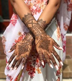 a woman's hands with hennap and flowers painted on her arms, both holding