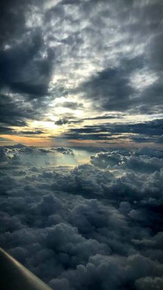 the view from an airplane looking down on clouds and sun rays in the sky above