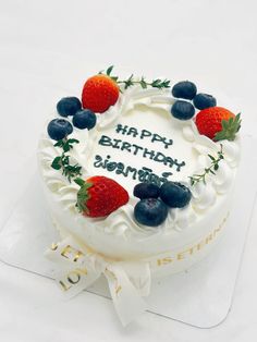 a birthday cake with strawberries and blueberries on it