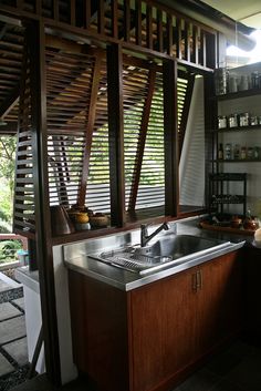 a kitchen with wooden slats on the ceiling and stainless steel sink in the center