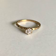 a yellow gold ring with a single diamond in the center on a white table top