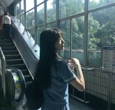 a woman standing in front of an escalator next to a set of stairs