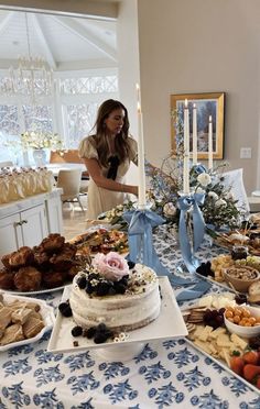 a woman standing in front of a table filled with cakes and pastries on it