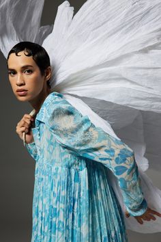 a woman in a blue dress with white wings on her head