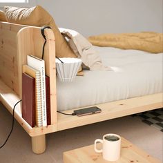 a bed that has some books on it and a coffee cup in front of it