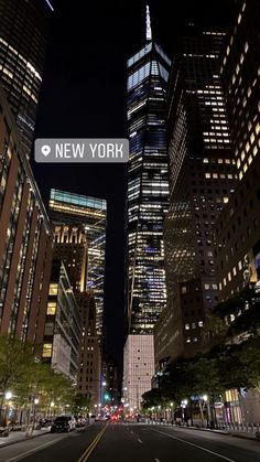 the new york sign is lit up in front of tall buildings at night, with street lights on either side