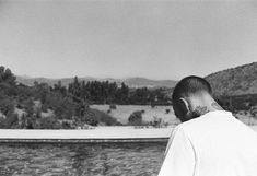 a black and white photo of a man looking out over the water