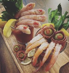 a wooden tray topped with different types of food next to lemon wedges and olives