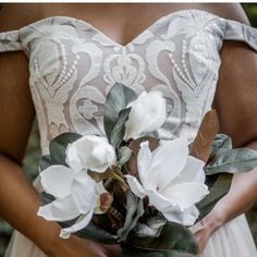 a woman in a dress holding a bouquet of flowers with leaves on the bottom half of her body