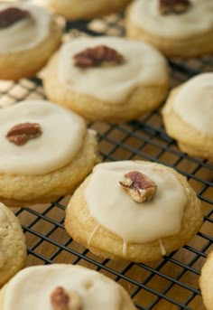 cookies with white icing and pecans on a cooling rack