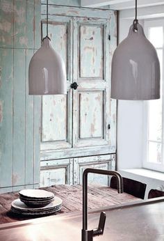 two lights hanging over a kitchen counter next to a sink and cabinets in a room