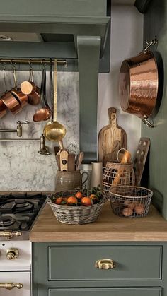 a kitchen with copper pots and pans hanging on the wall above the stove top