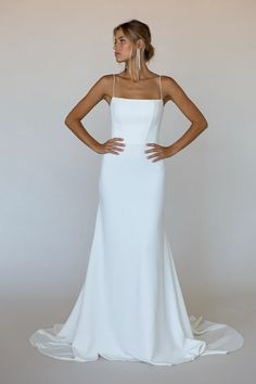 a woman in a white wedding dress standing with her hands on her hips and looking off to the side