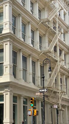 a tall white building with many windows next to a traffic light and street sign in front of it