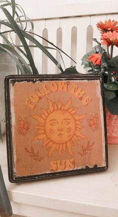 a wooden sign sitting on top of a white bench next to flowers and potted plants