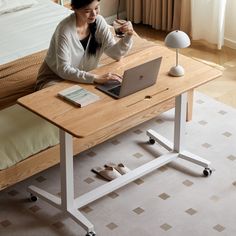 a woman sitting at a table with a laptop on her lap and holding a cup