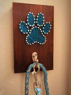 a blue and white leash hanging on a wall with a wooden sign that says dog paw