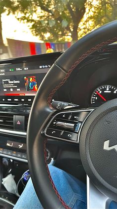 the interior of a car is shown with red stitchs on the steering wheel and dashboard