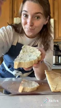 a woman in an apron holding up a piece of bread