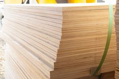 several wooden boards stacked on top of each other with green tape around the edges and yellow vases in the background