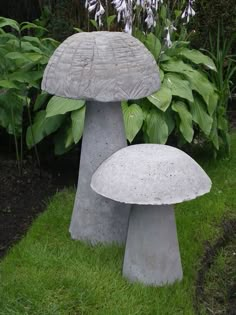 two cement mushrooms sitting on top of green grass