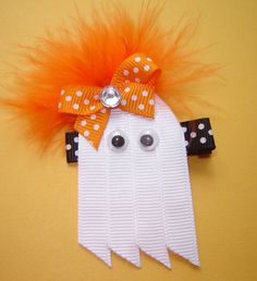 a white ghost with orange hair and polka dots on it's head, sitting on a yellow surface