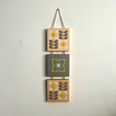 two wooden blocks hanging on a wall with flowers painted on them and one has a ring in the middle