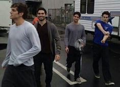 four men walking down the street in front of an rv