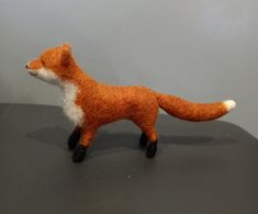 a needle - felt fox standing on top of a table