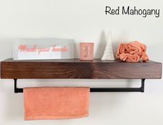 a bathroom shelf with towels, cups and napkins on it next to a red mahogany towel rack