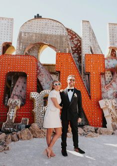 a man and woman standing next to each other in front of the las vegas sign