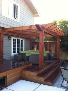 an outdoor patio with wooden decking and pergolated seating on the side of it