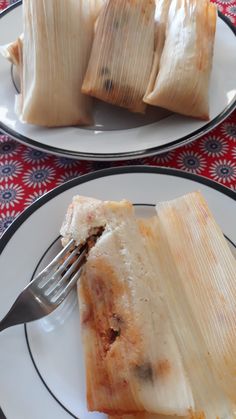 two plates with food on them, one is wrapped in paper and the other has a fork