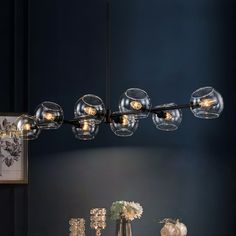 a modern chandelier hanging over a dining room table with vases and candles