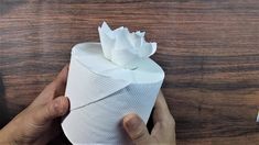 someone holding a roll of toilet paper on top of a wooden table