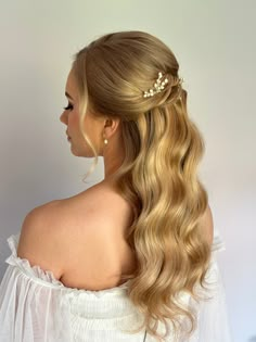 a woman with long blonde hair wearing a half updo and a flower in her hair