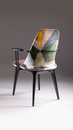 an upholstered chair with black legs and a multicolored fabric on it