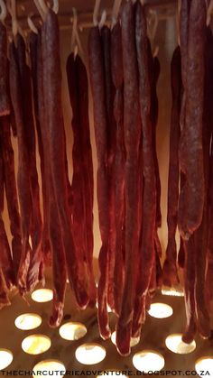 several sausages hanging from hooks in a food vendor's display case with lights around them