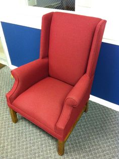 a red chair sitting on top of a carpeted floor next to a blue wall