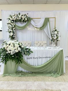 the table is set up with white flowers and greenery for an elegant wedding reception