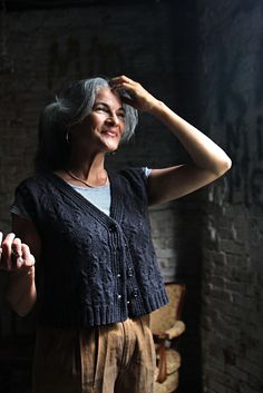 a woman standing in front of a brick wall