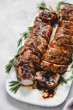 sliced pork on a plate with rosemary garnish and ketchup drizzled over it