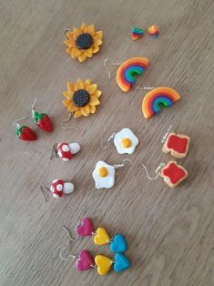 several different types of pins and magnets on a wooden surface with sunflower, rainbow, mushroom, apple, strawberry, cloud