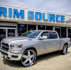 a silver truck is parked in front of a rim source store on a sunny day