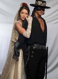 a man and woman dressed up as pirates posing for a photo in front of a white backdrop