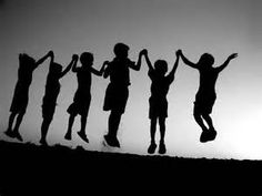 a group of kids jumping in the air with their hands up and arms extended, silhouetted against an overcast sky